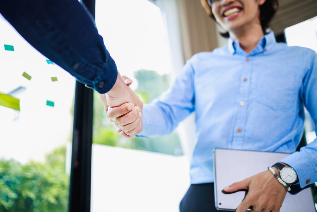 Young business professional shaking hands with a client to build rapport.