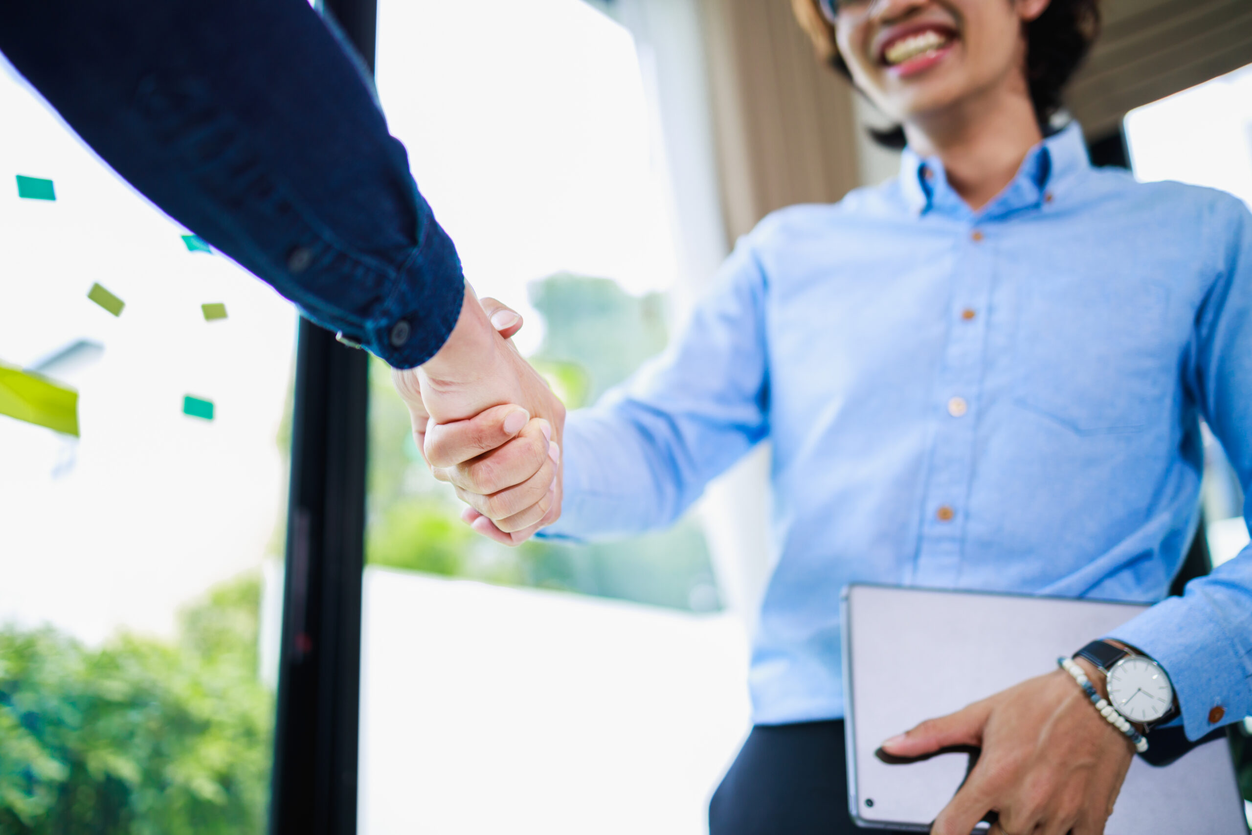 Young business professional shaking hands with a client to build rapport.