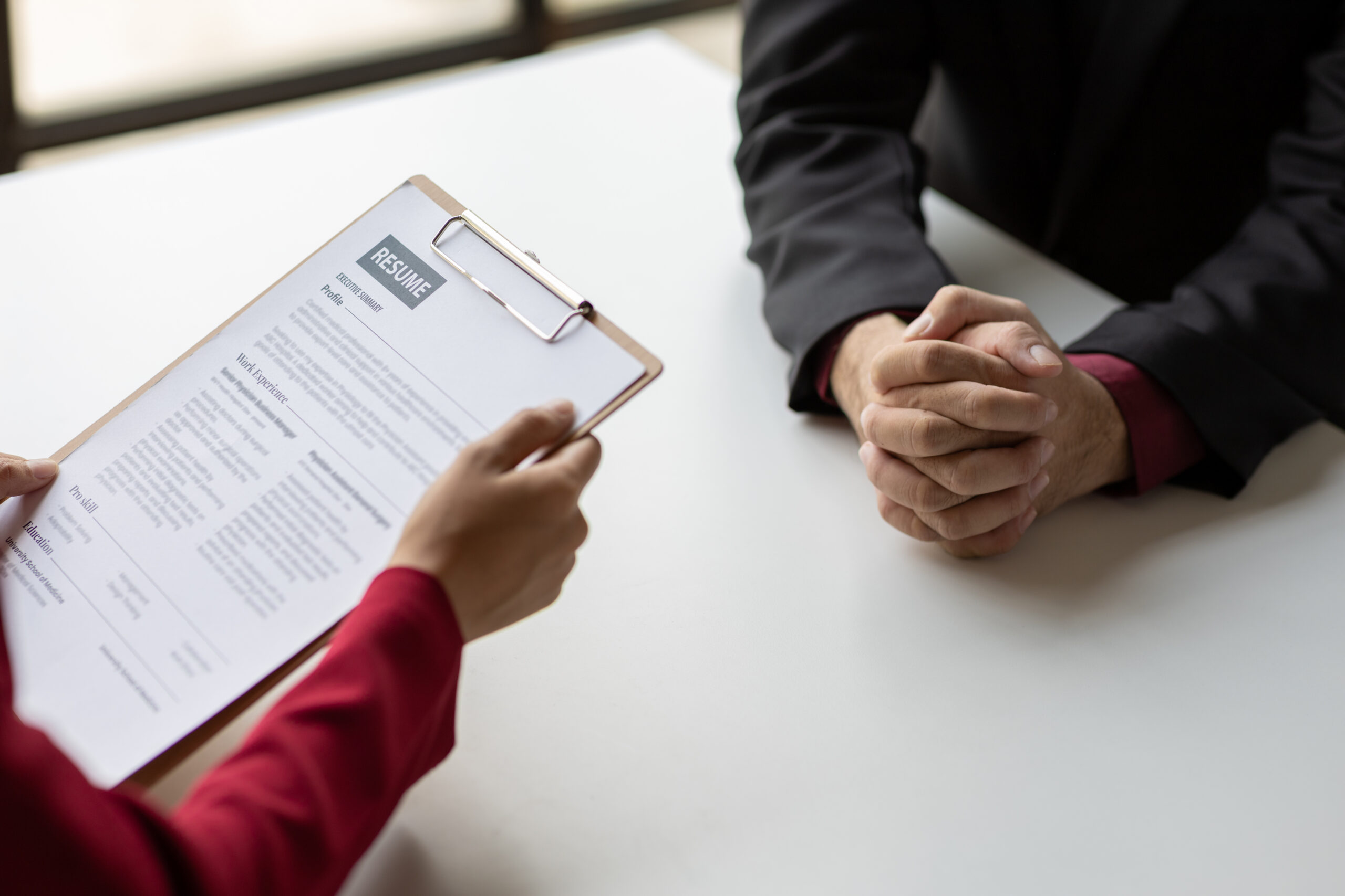 A job interviewer holding a clipboard with an applicant’s resume on it